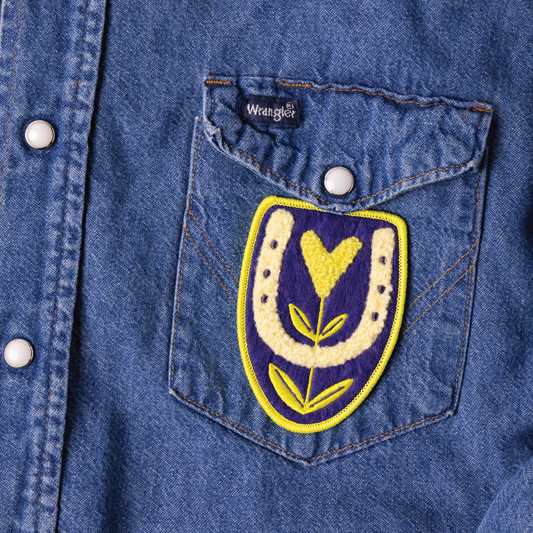 Denim pocket with embroidered patch featuring a yellow flower on a blue denim background