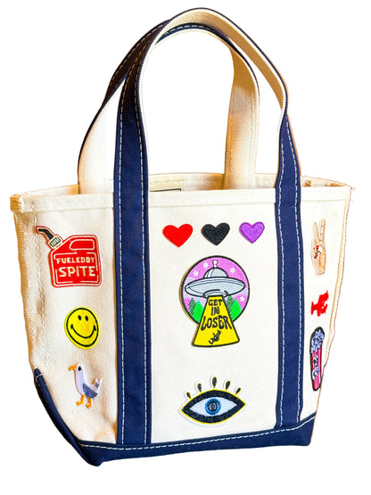 Tote bag with various colorful stickers on a wooden surface