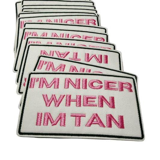 Stack of patches with text 'I'M NICER WHEN I'M TAN' on a white background