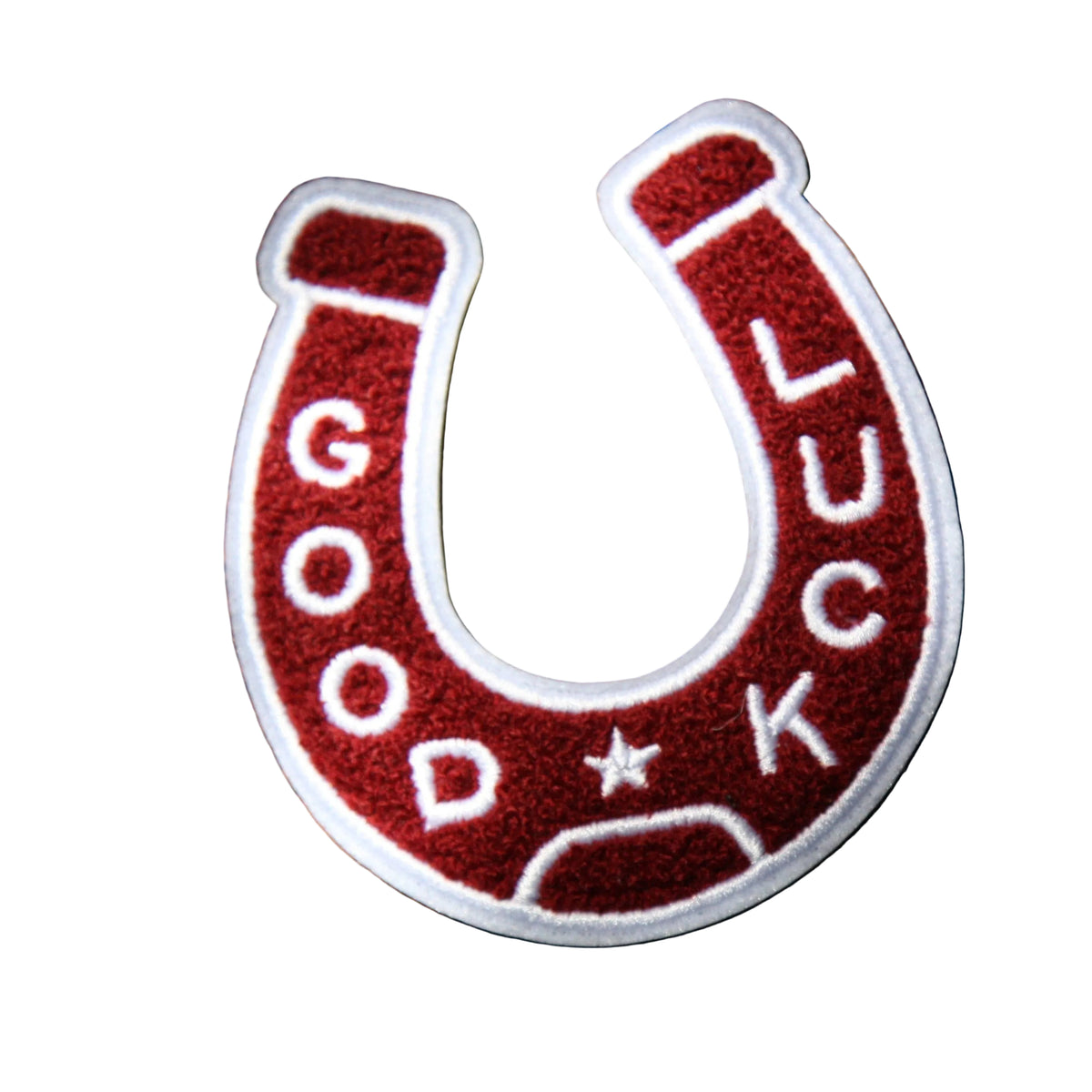 Red and white horseshoe patch with 'Good Luck' text on a wooden surface