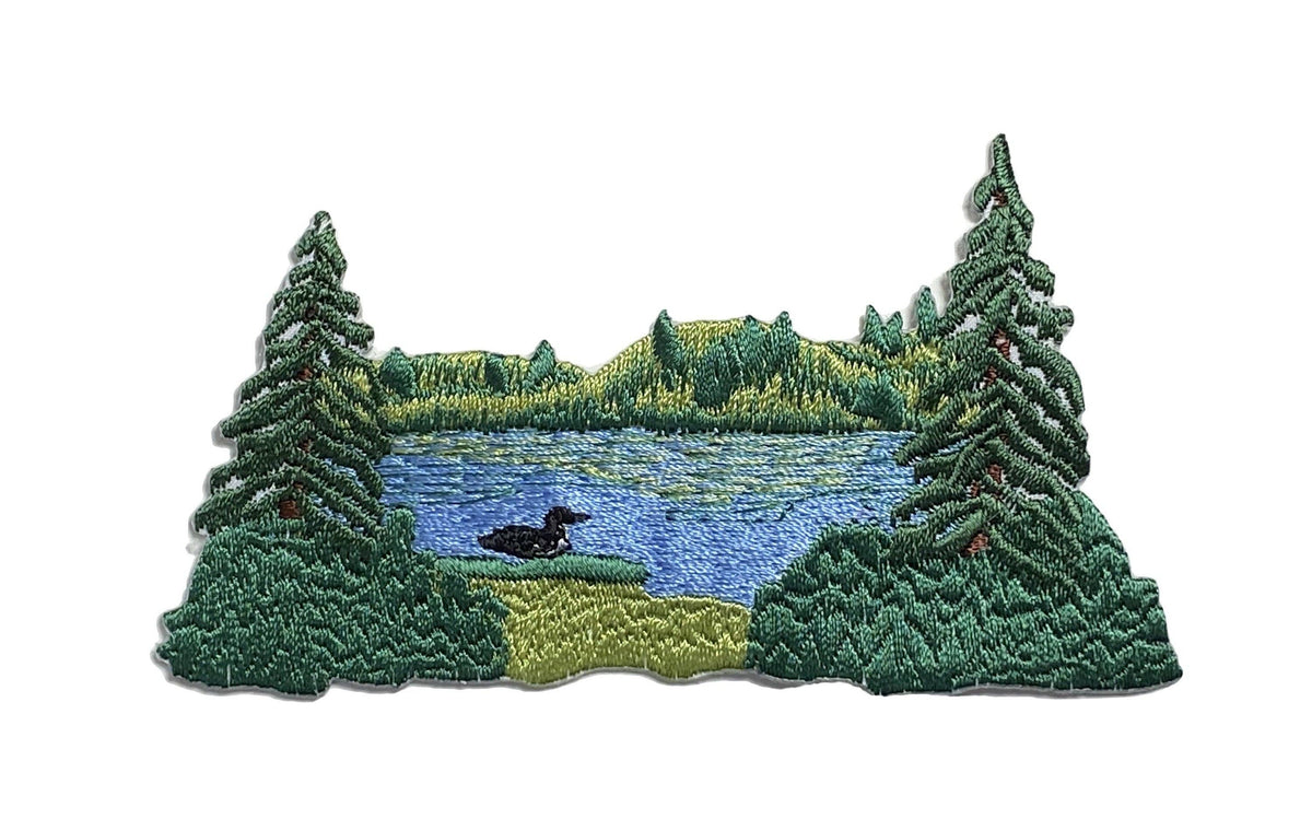Embroidered patch of a forest lake scene with trees and a duck.