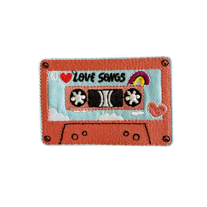 Patch of a retro cassette tape with 'Love Songs' text on a white background