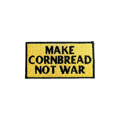 Embroidered patch with 'MAKE CORNBREAD NOT WAR' text on a yellow background