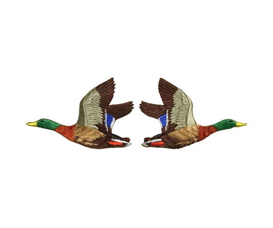 Two embroidered duck patches on a beige fabric background