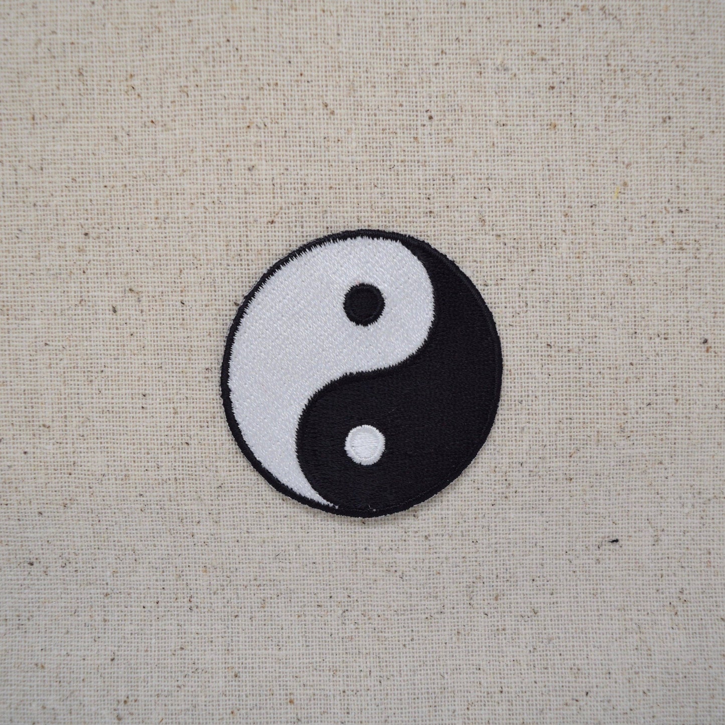 Yin and yang symbol on a textured beige background