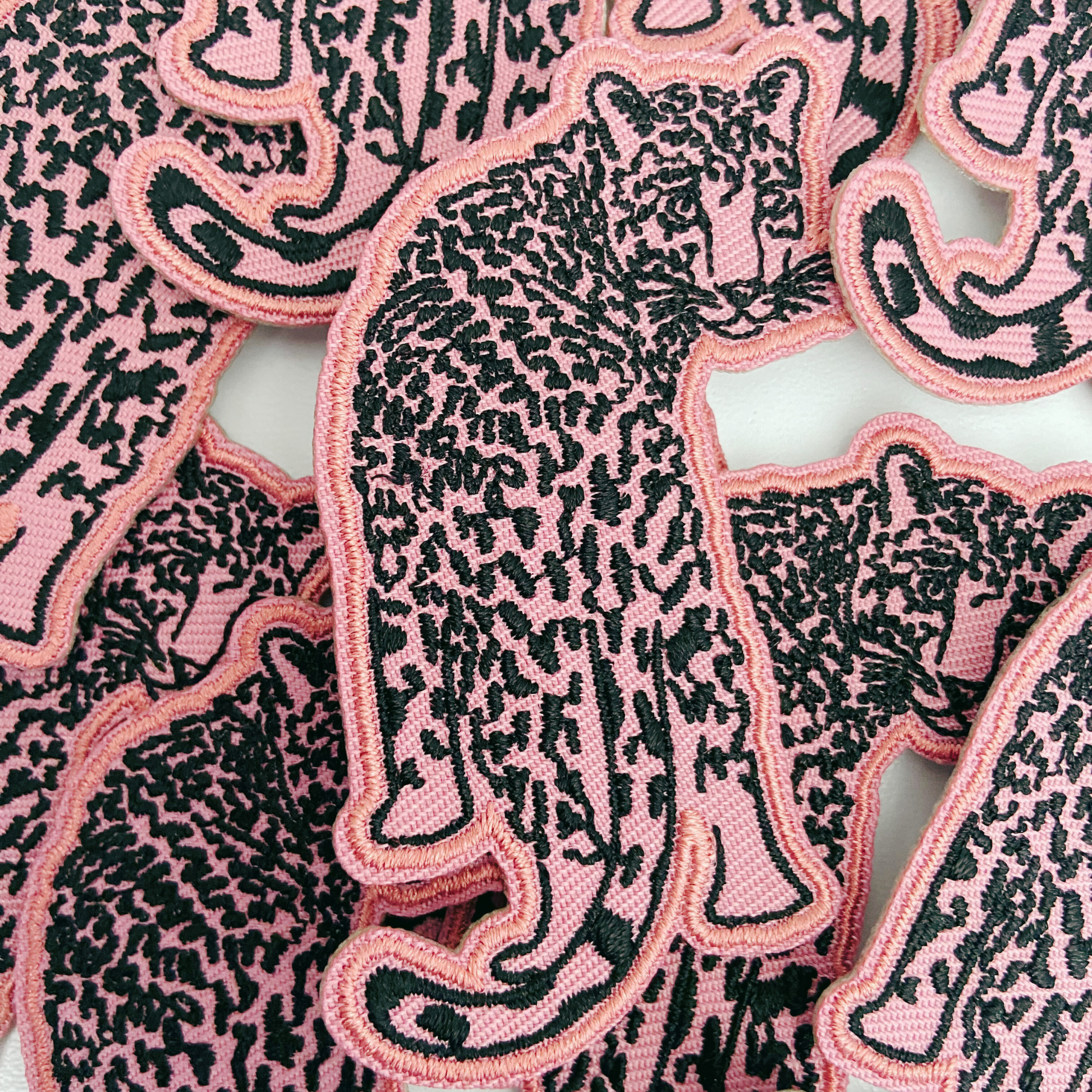 Pink and black panther patches on a white background