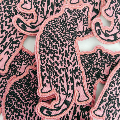 Pink and black panther patches on a white background