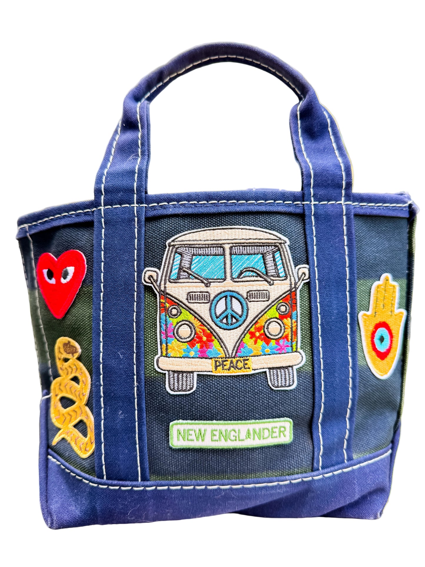 Blue bag with colorful patches including a van, heart, and peace symbol on a blurred natural background.
