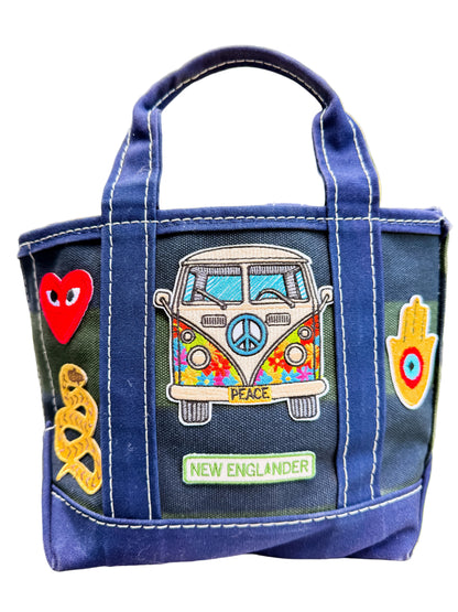 Blue bag with colorful patches including a van, heart, and peace symbol on a blurred natural background.