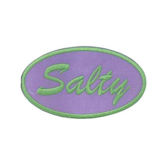 An oval embroidered patch with a lavender purple background, a light green border, and the word 'Salty' stitched in light green script across the center, shown on a plain white background.