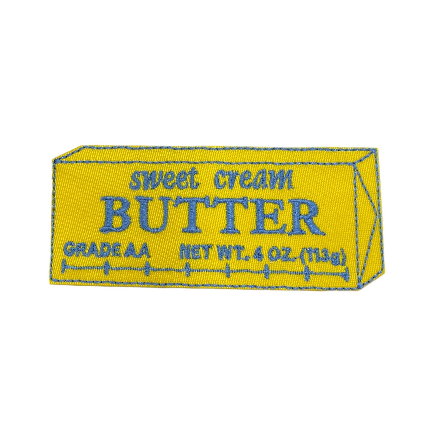 A yellow rectangular patch designed to look like a butter stick, with blue embroidered text reading 'sweet cream BUTTER GRADE AA NET WT. 4 OZ.