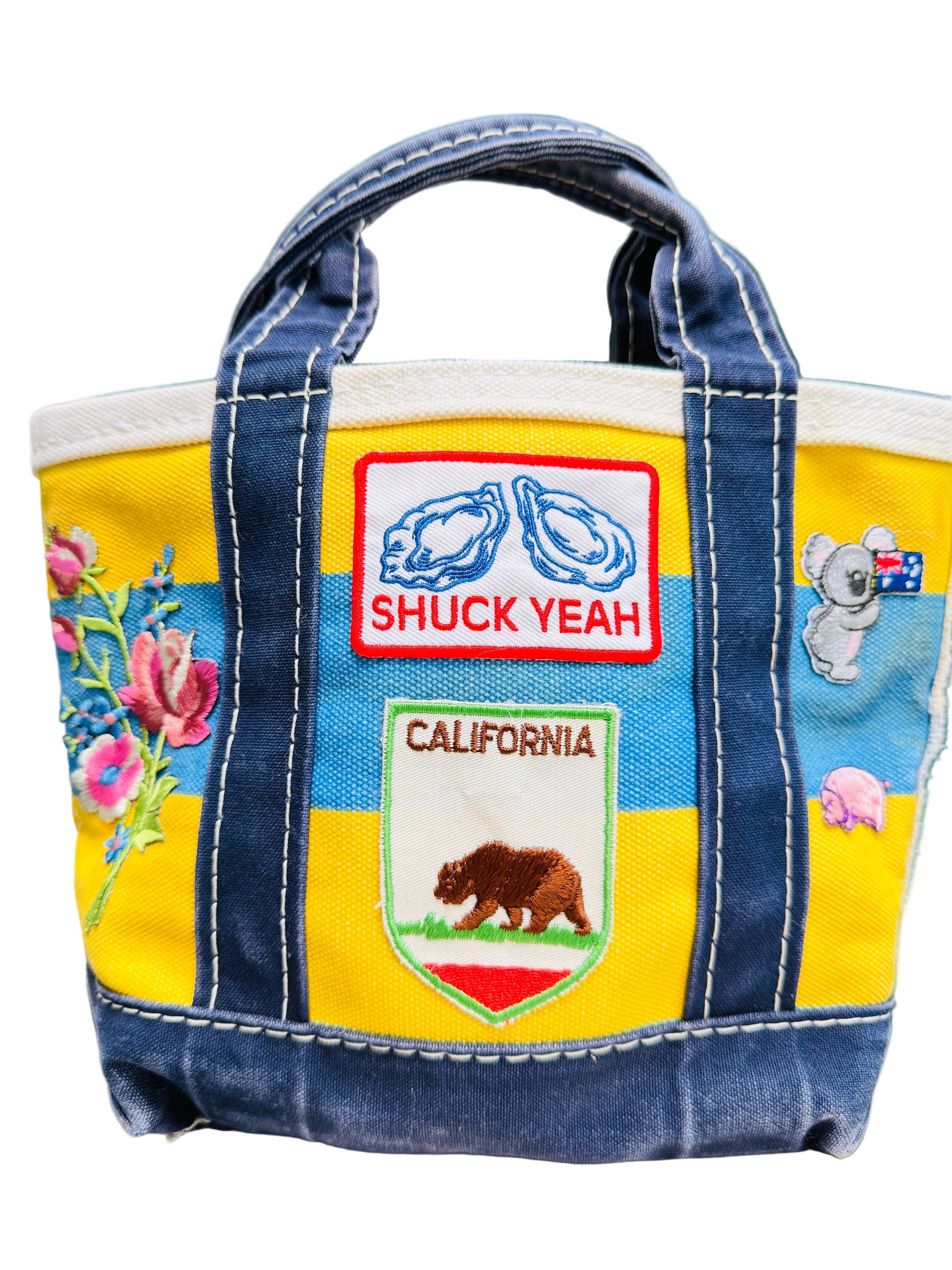 Colorful bag with patches including 'Shuck Yeah' and 'California' on a wooden surface.