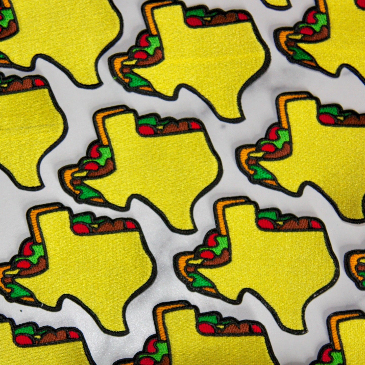 Pattern of yellow Texas-shaped patches with food items on a white background