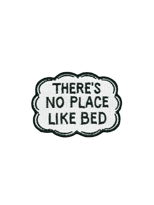 Embroidered patch with text 'THERE'S NO PLACE LIKE BED' on a white background
