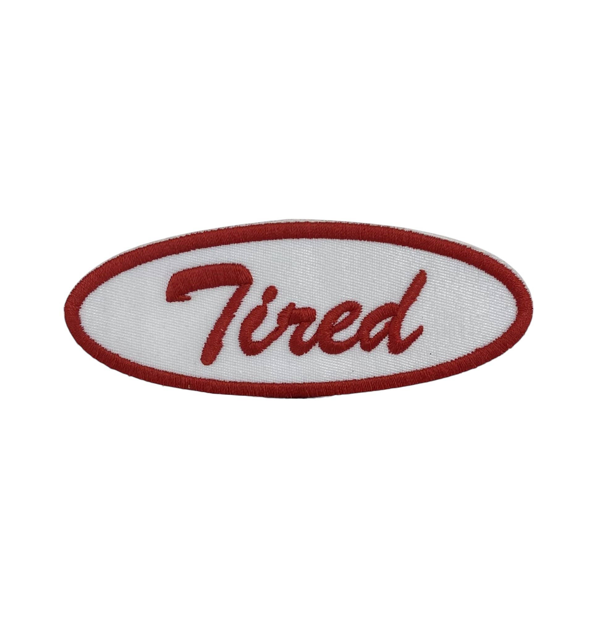 Embroidered patch with 'Tired' text on a white background