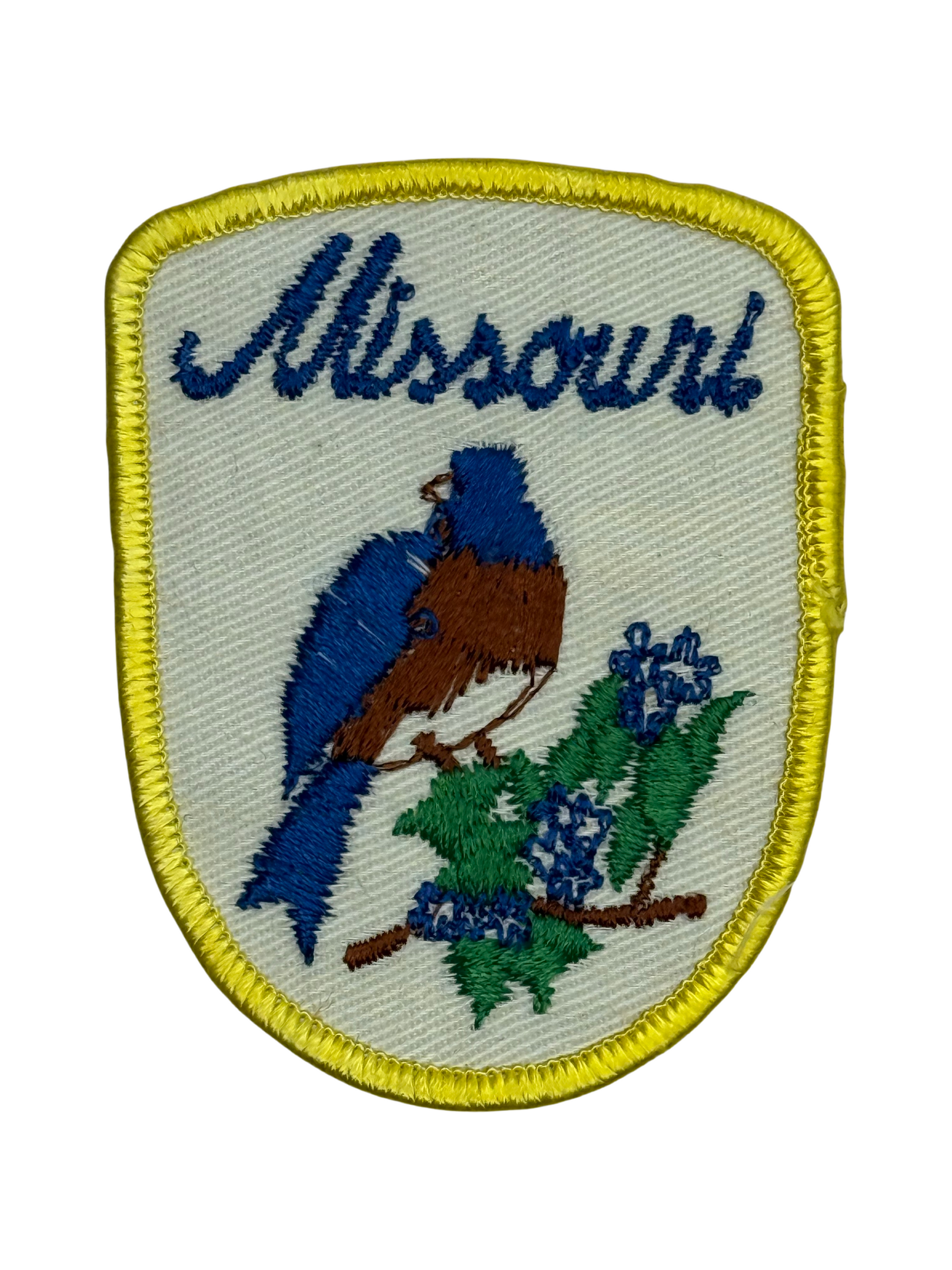 Embroidered patch with a blue bird and flowers, featuring the word 'Missouri'.
