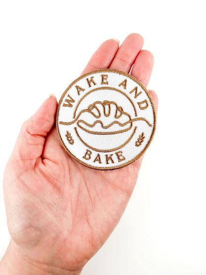 Hand holding a 'Wake and Bake' patch with a white background