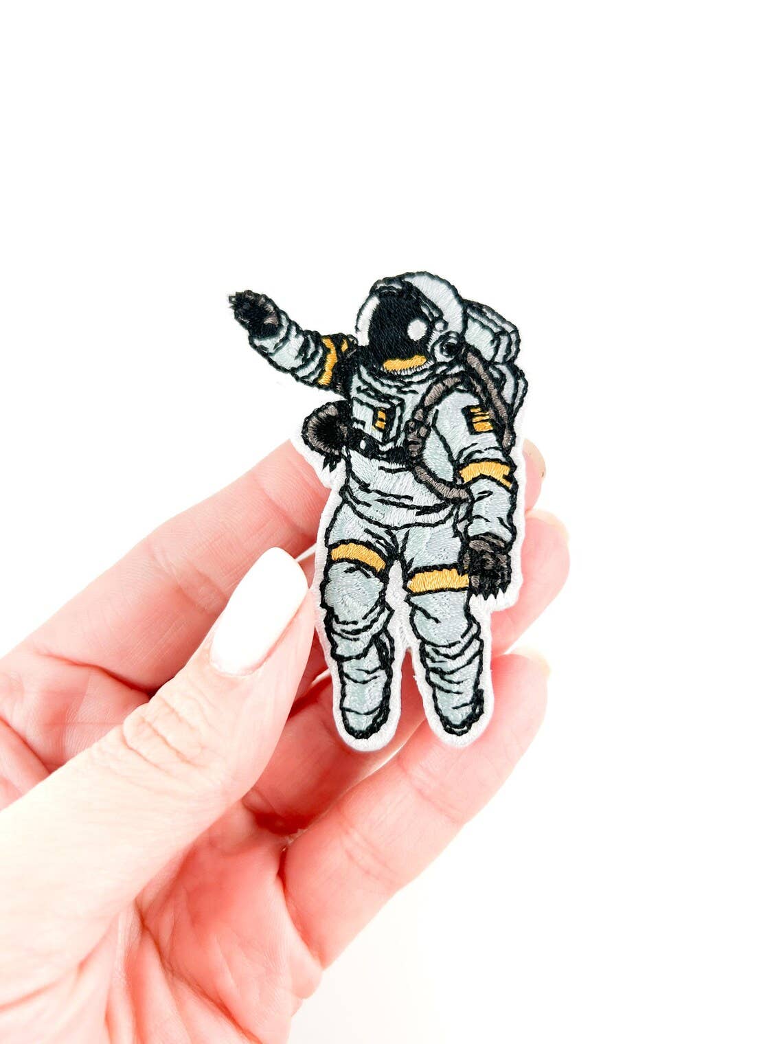 Hand holding an astronaut patch on a white background