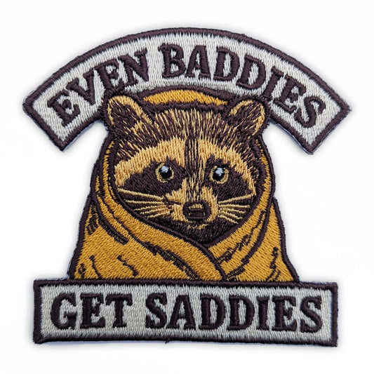 Embroidered patch with raccoon illustration and text 'Even Baddies Get Saddies' on a white background
