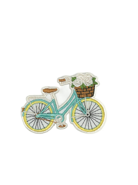 Teal bicycle with a basket of flowers patch on a white background