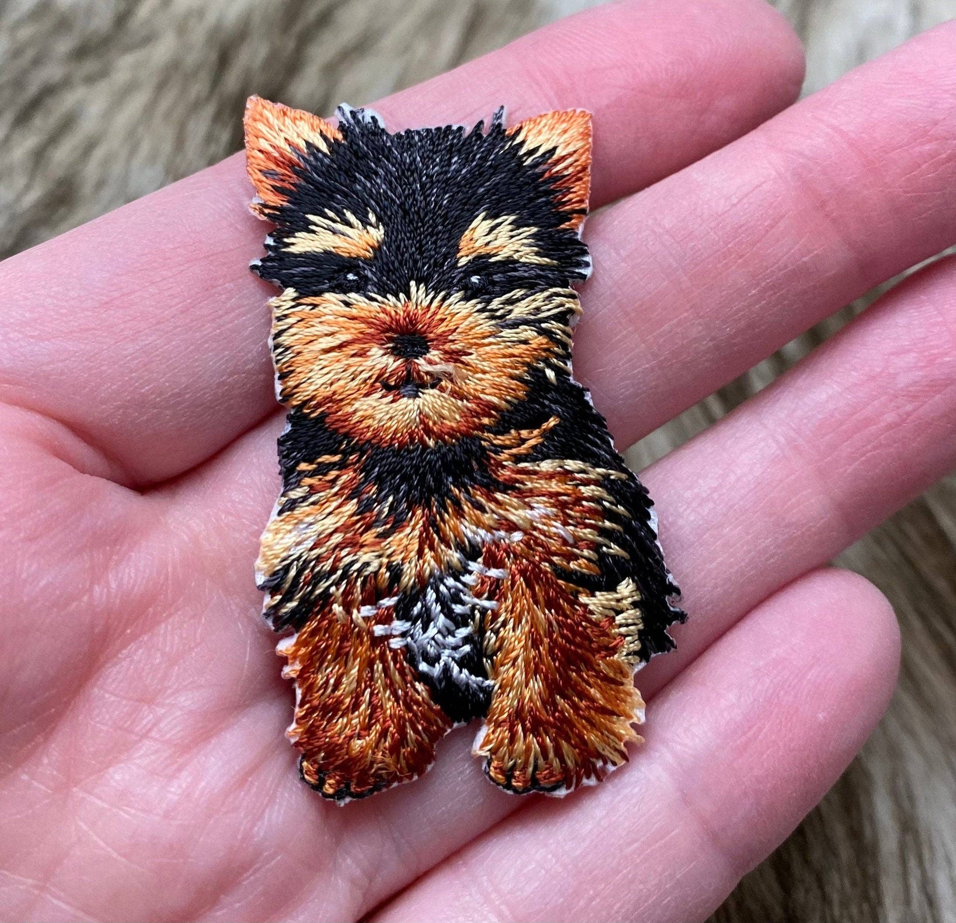 Embroidered patch of a dog held in a hand
