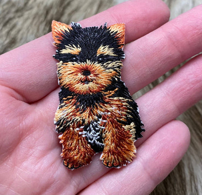 Embroidered patch of a dog held in a hand