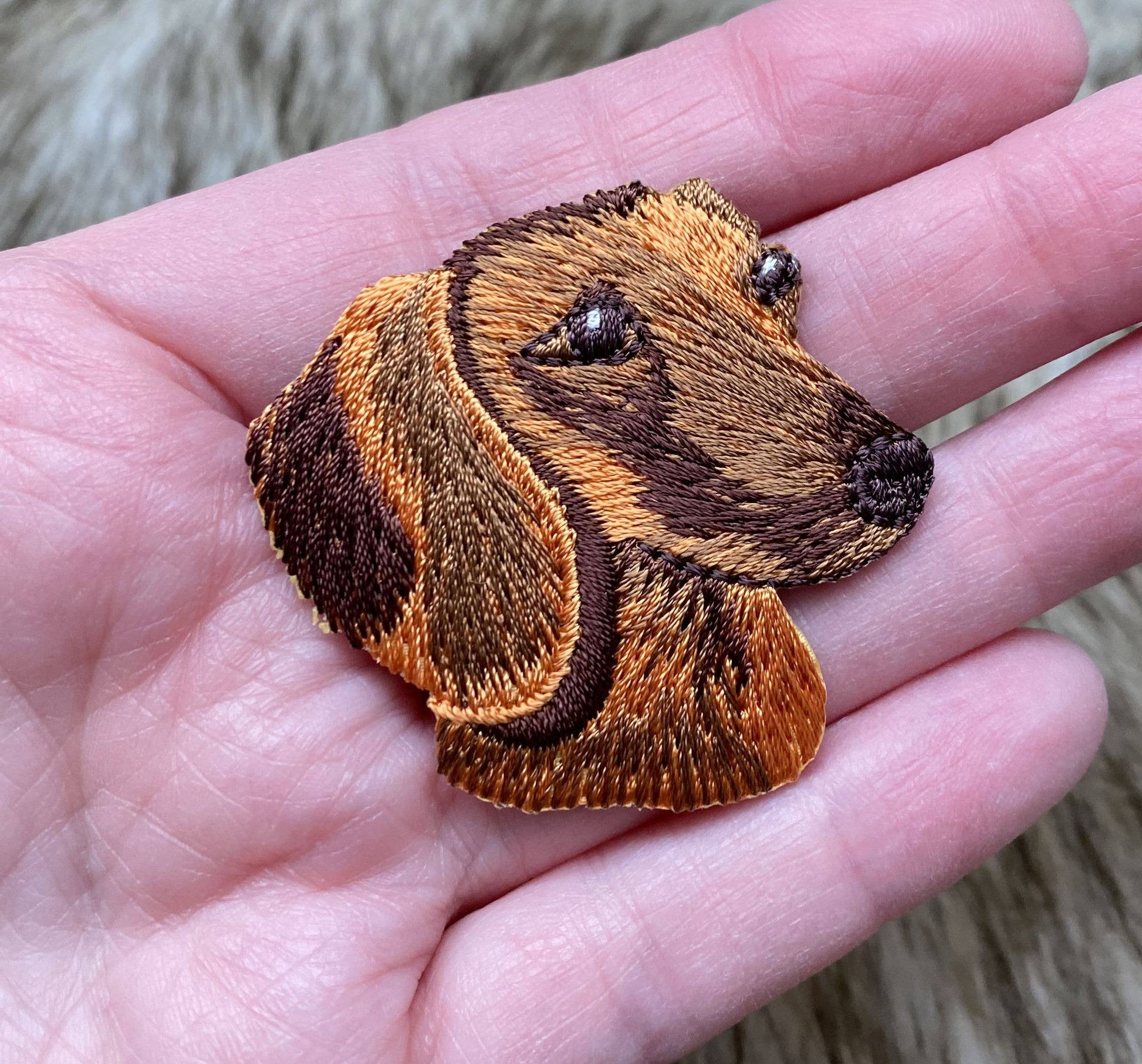 Embroidered patch of a dog's face held in a hand