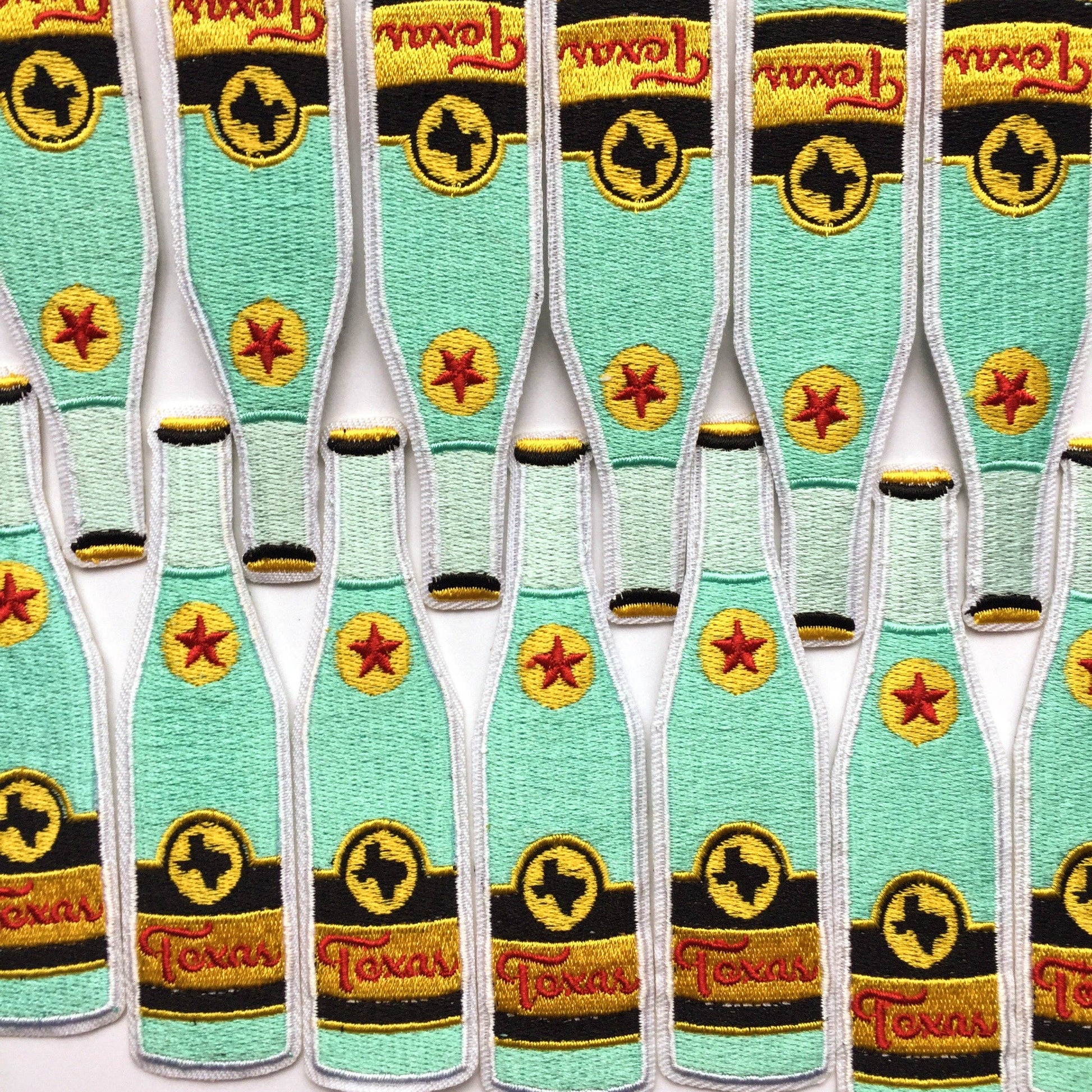Multiple embroidered patches of a bottle with Texan logo