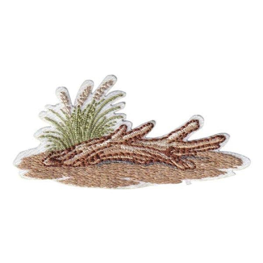 Embroidered patch of driftwood on beach with sea grass with a white background