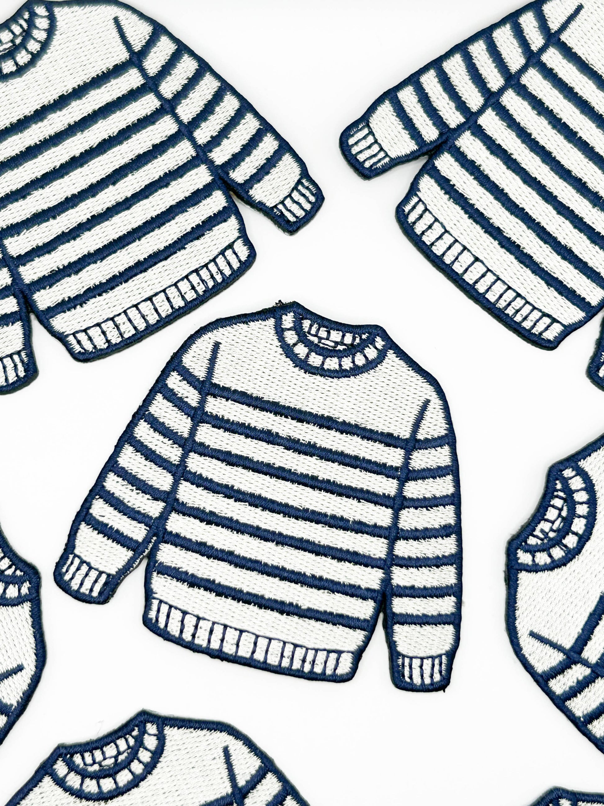 Pattern of navy and cream striped sweaters on a white background