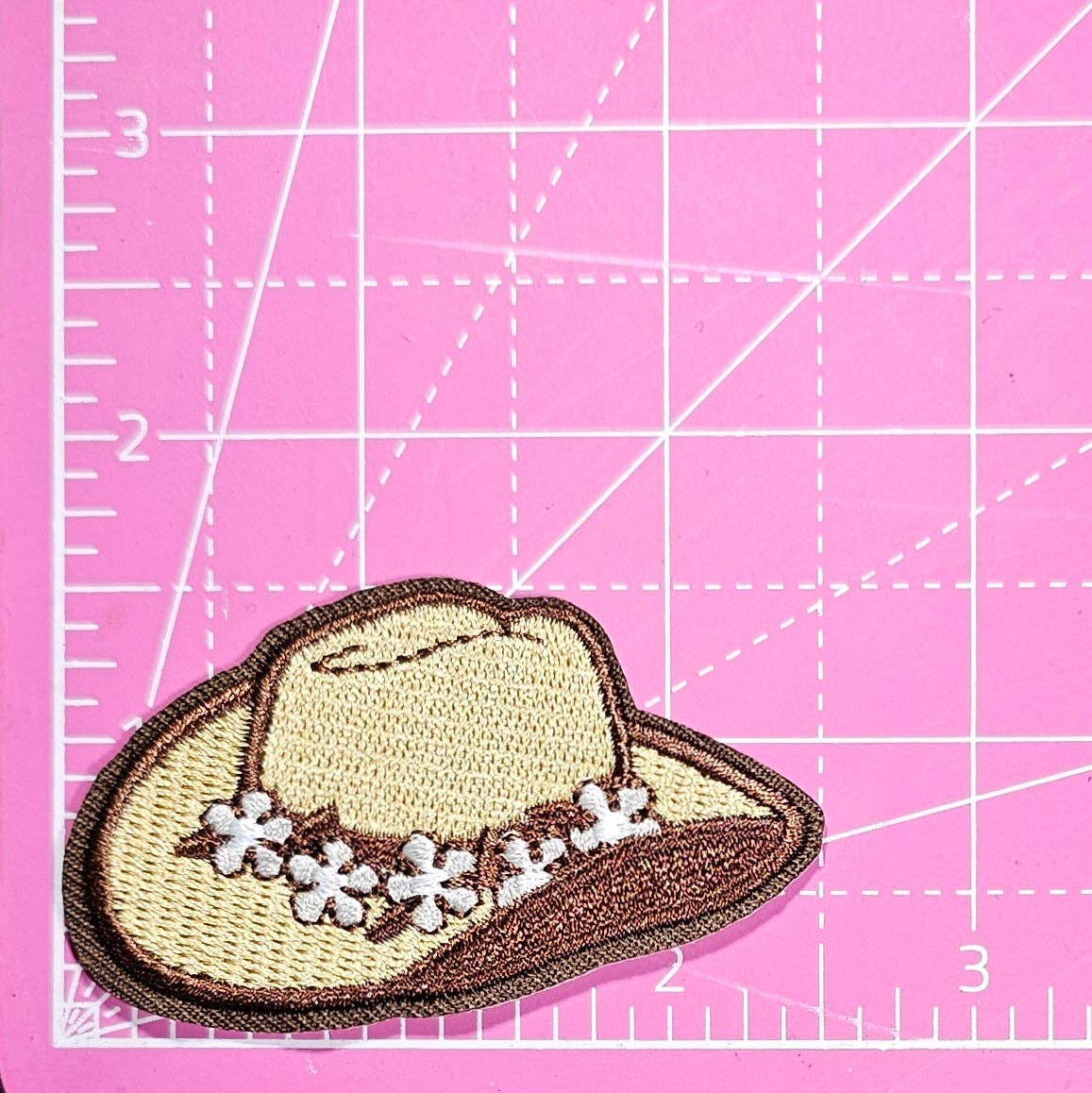 Cowgirl hat patch with flowers on a pink cutting mat