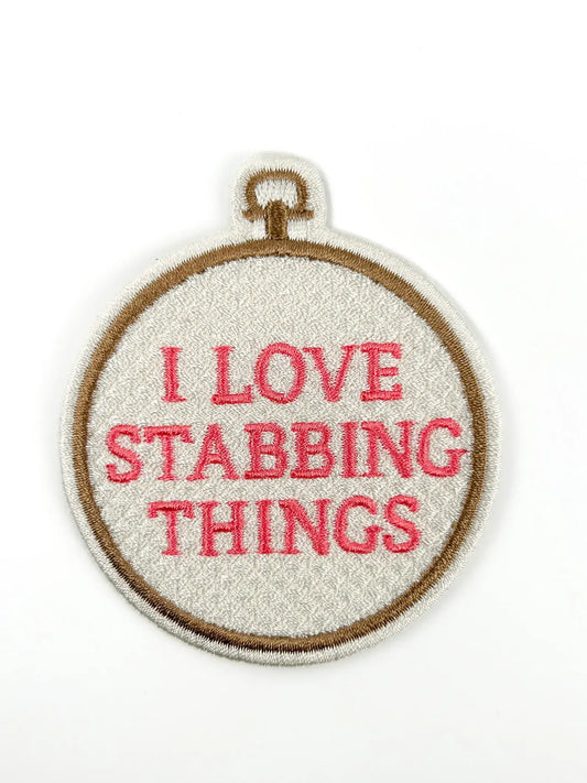 Patch design with an embroidery hoop with 'I love stabbing things' text on a white background