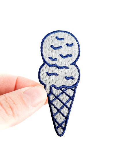Embroidered ice cream cone patch held by a hand on a white background