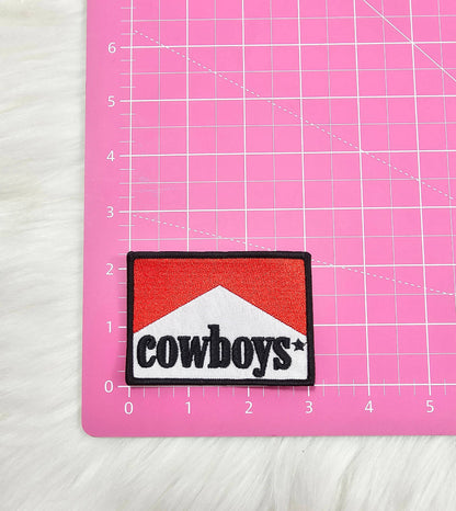 Patch with 'cowboys' text on a pink cutting mat