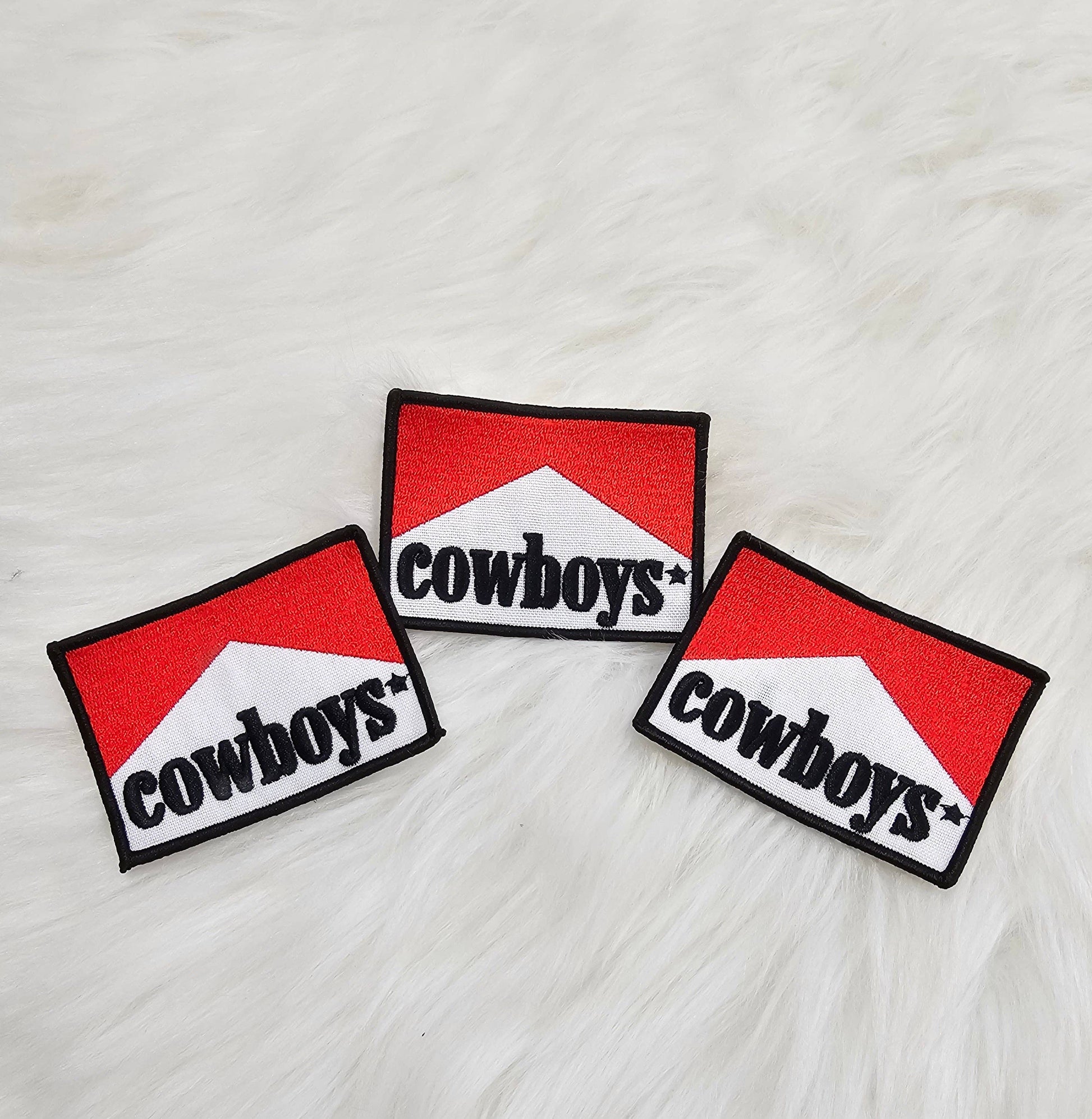 Three 'cowboys' patches on a textured white surface