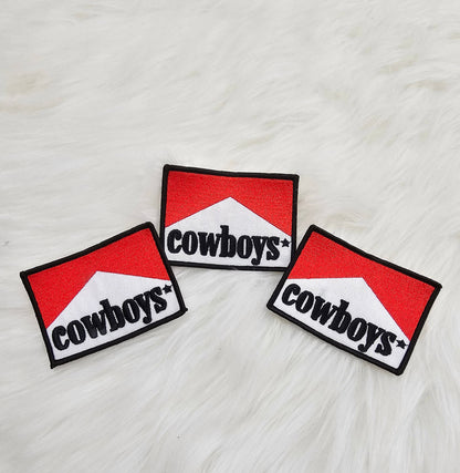 Three 'cowboys' patches on a textured white surface