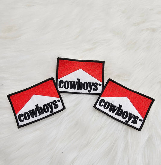 Three 'cowboys' patches on a textured white surface