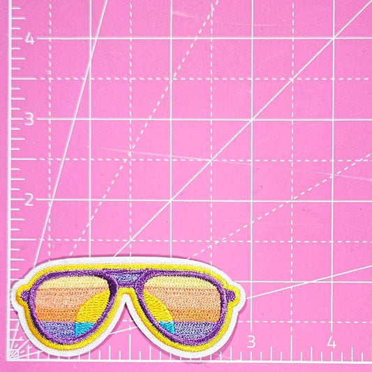 Sunglasses patch on a pink cutting mat with grid lines