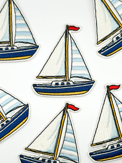Pattern of sailboats patches with striped sails on a white background