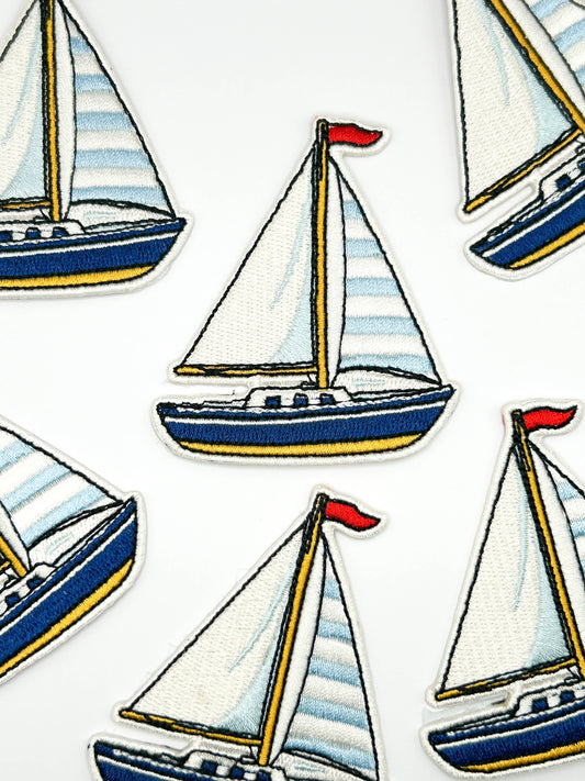 Pattern of sailboats patches with striped sails on a white background
