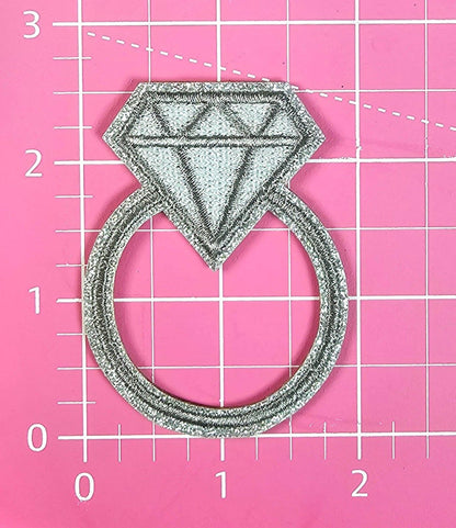 Embroidered diamond ring patch on a pink background.