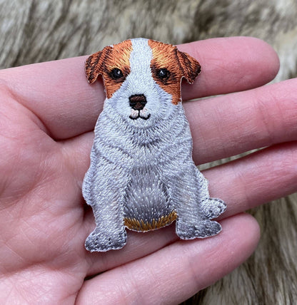 Embroidered patch of a dog held in a hand