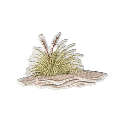 An embroidered patch with seagrass on the beach with a white background