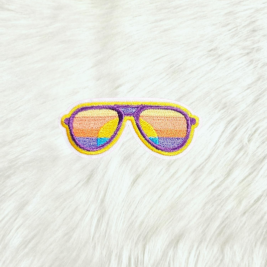 Embroidered patch of sunglasses with sunset lenses on a white fabric background