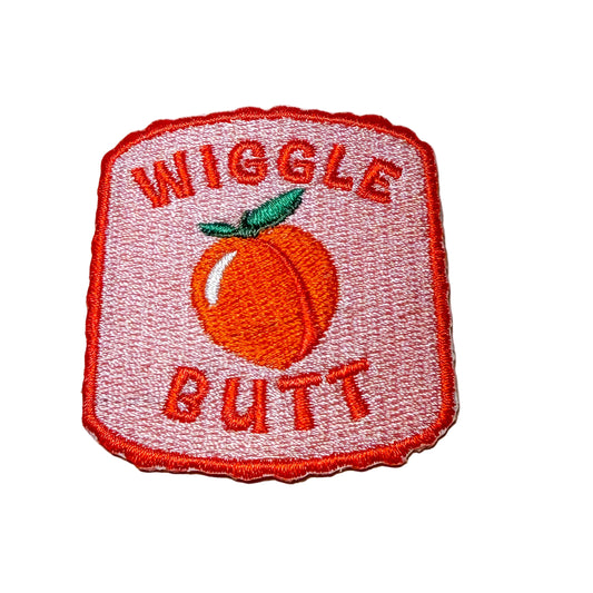 Embroidered patch with 'Wiggle Butt' text and peach graphic on a white background