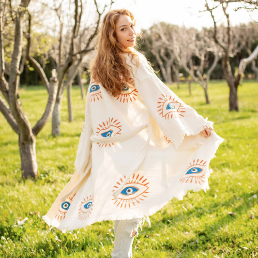 Woman wearing a white dress with eye designs in a grassy field