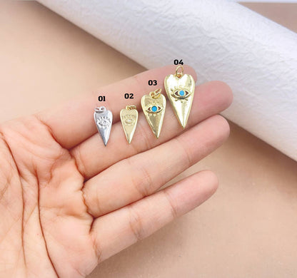 Four gold evil eye heart pendants on a hand with a white cloth background