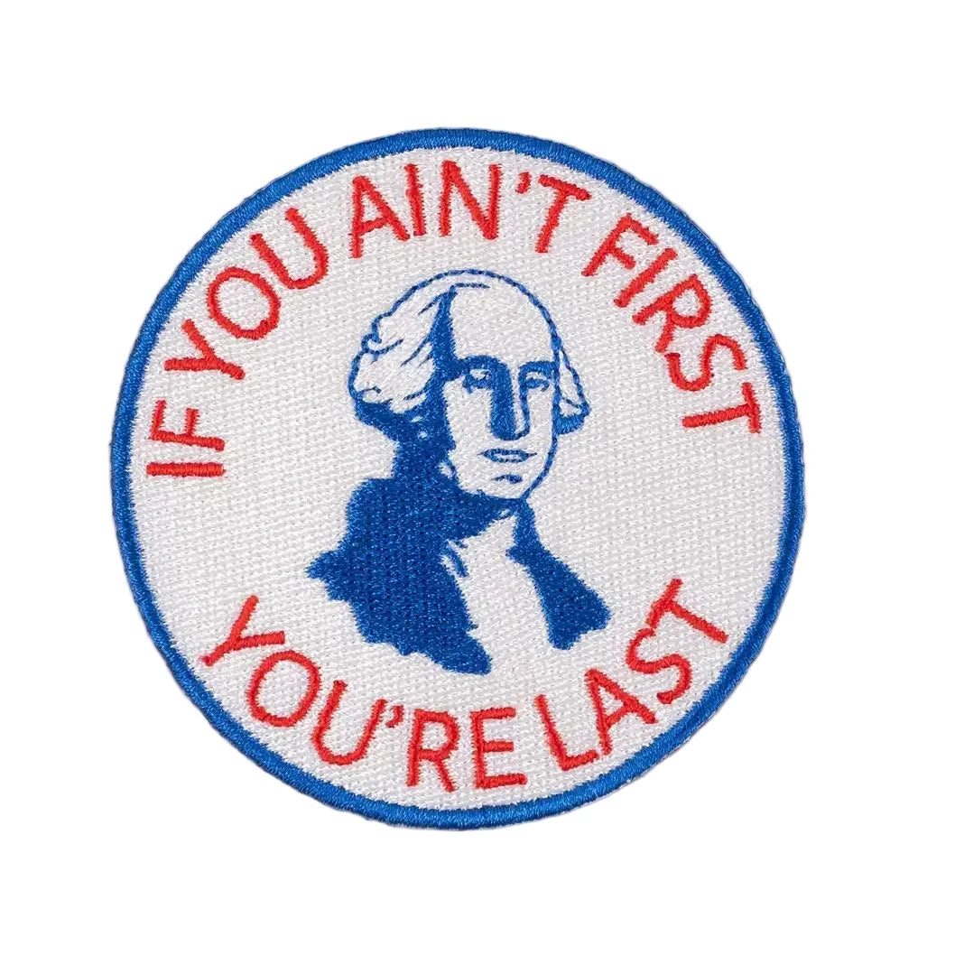 Patch with a portrait and text 'If you ain't first, you're last' on a beige background