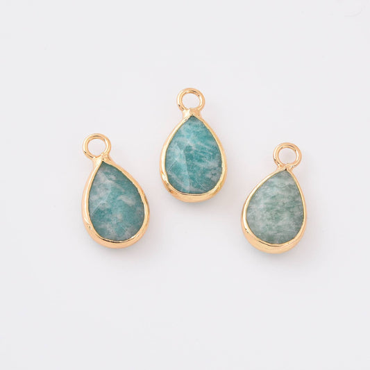 Three teardrop-shaped amazonite pendants with gold frames and green stones on a white background