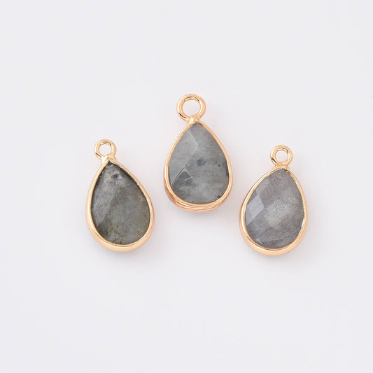 Three teardrop-shaped labradorite gemstone pendants with gold frames on a white background